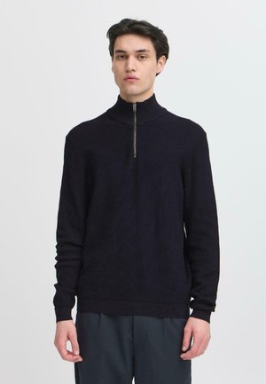 Dark navy knit sweater with a high collar and half-zip closure. Features ribbed texture and long sleeves. Smooth, fitted design.