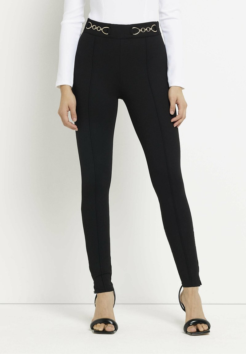 Zwarte leggings met een hoge tailleband voorzien van gouden cirkelvormige accenten, een gladde textuur, een nauwsluitend ontwerp en opvallende naaddetails.