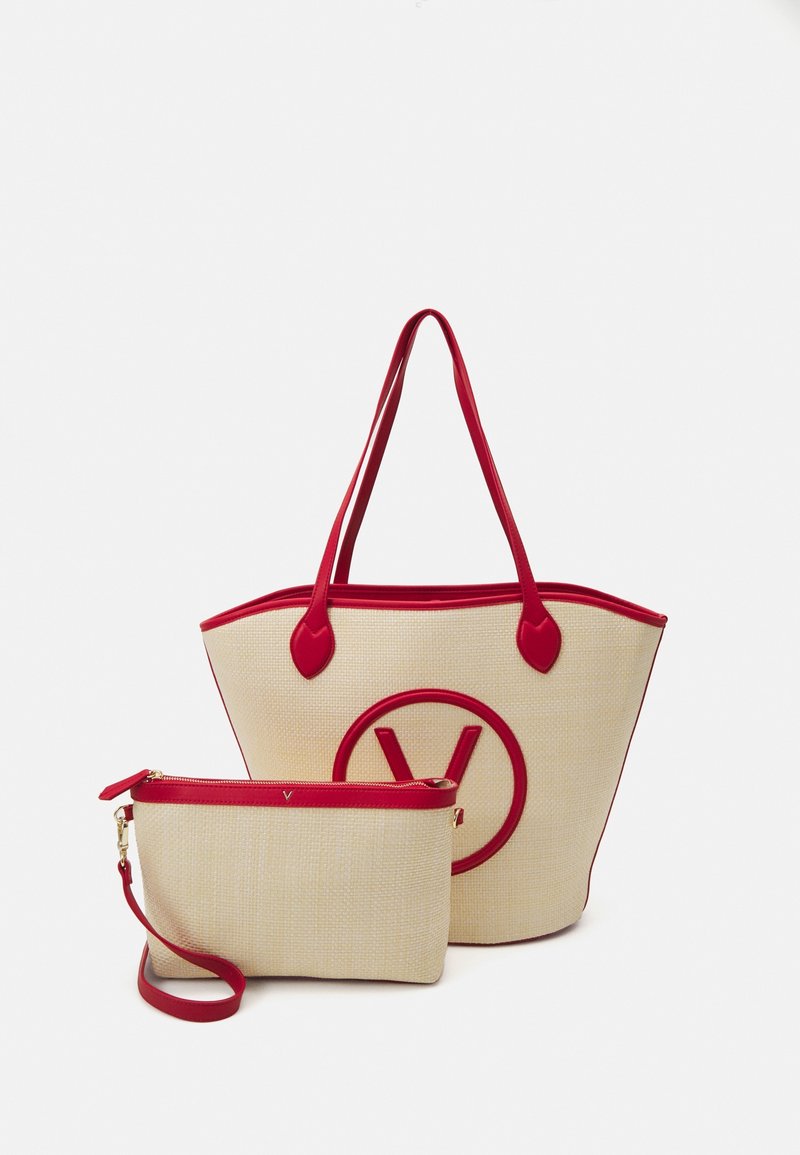 Stor beige axelväska med röda detaljer och en rund logo; i kombination med en mindre clutch, också beige med en röd dragkedja och rem.