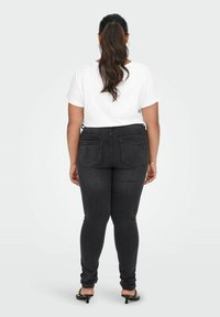 Zwarte skinny jeans van denim, met twee achterzakken en een schone tailleband. Gecombineerd met een eenvoudig wit T-shirt en zwarte sandalen.