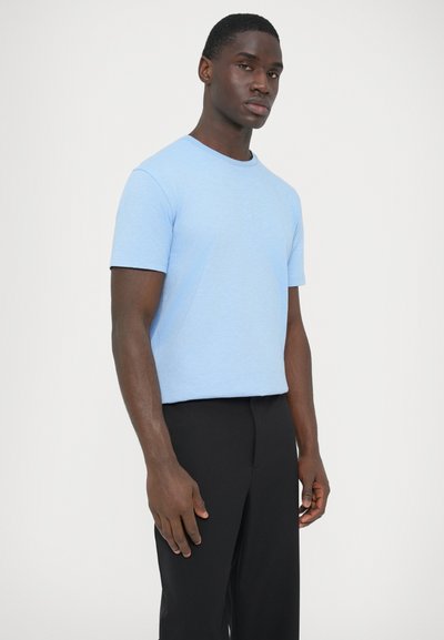 Ανοιχτό μπλε βαμβακερό μπλουζάκι με κοντά μανίκια, στρογγυλή λαιμόκοψη και άνετη εφαρμογή, σε συνδυασμό με μαύρο παντελόνι. Λεπτή υφή, με ελάχιστες λεπτομέρειες.