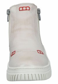 White leather ankle boot featuring red accents, side zippers, and a textured rubber sole with a ridged pattern.