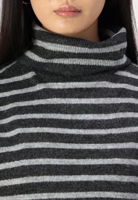 Maglione a collo alto a righe grigio e grigio chiaro, caratterizzato da un morbido tessuto lavorato con un fit rilassato e un colletto alto.