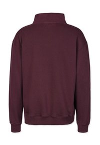 Burgundy collegepaita korkealla kauluksella, laskettu olkapää, ribattu hihansuu ja helma. Pehmeä rakenne sileällä pinnalla, ilman näkyviä kuvioita.