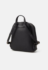 Zaino in pelle nera con forma strutturata, manico superiore, spallacci regolabili e dettagli in metallo dorato. Texture liscia con un design minimalista.