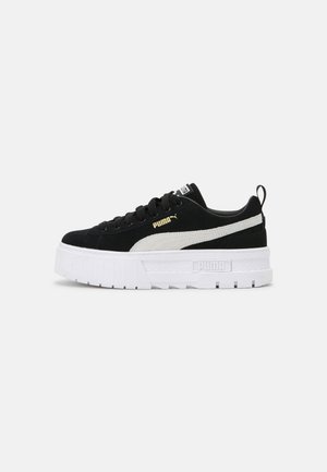 Czarnobiały sneaker Puma z grubą białą podeszwą na platformie, białym paskiem po boku, czarnymi sznurowadłami i złotym logo Puma.