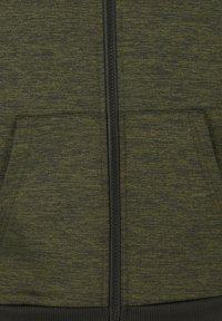 Grøn tekstureret hættetrøje med lynlås foran, to håndlommer og sorte detaljer langs lynlåsen og kanten. Stoffet virker blødt og varmt.