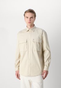 Beige langlopende overhemd met knoopsluiting en twee borstzakken, met een puntkraag, vervaardigd uit een gladde stof en voorzien van een klein logo-accent.