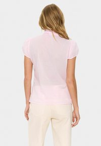 Pink short-sleeve blouse with puffed shoulders, lightweight fabric, and a relaxed fit. Smooth texture and simple back design.
