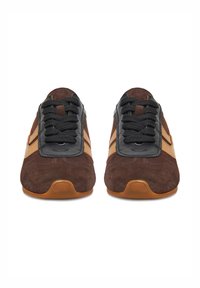 Brūni zamšādas tenisi ar melniem auklām, ādas akcentiem un gumijas zoli. Sānos ir viegli brūnas svītras. Gludas un teksturētas virsmas.