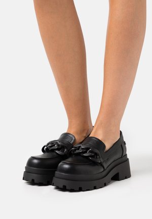 Bottines compensées noires avec un détail en chaîne épais, en cuir lisse, à bout rond et semelle en caoutchouc texturé.