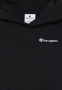Hanorac negru din material, cu un buzunar frontal, glugă cu șnur și logo-ul alb brodat "Champion" pe piept.