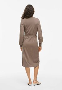 Robe longue à manches longues marron avec une taille ceinturée, silhouette mi-longue, tissu doux et poignets ajustés. Design simple et uni sans motifs.