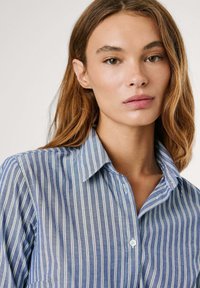 Camicia a maniche lunghe a righe blu e bianche con colletto, realizzata in un tessuto leggero e texturizzato, dal fitting rilassato.