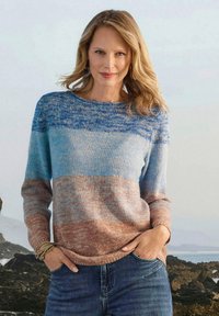 Maglione a maglia con strisce orizzontali blu e marrone sabbia, collo a giro, e maniche lunghe. Texture morbida, vestibilità rilassata. Indossato con jeans di denim.