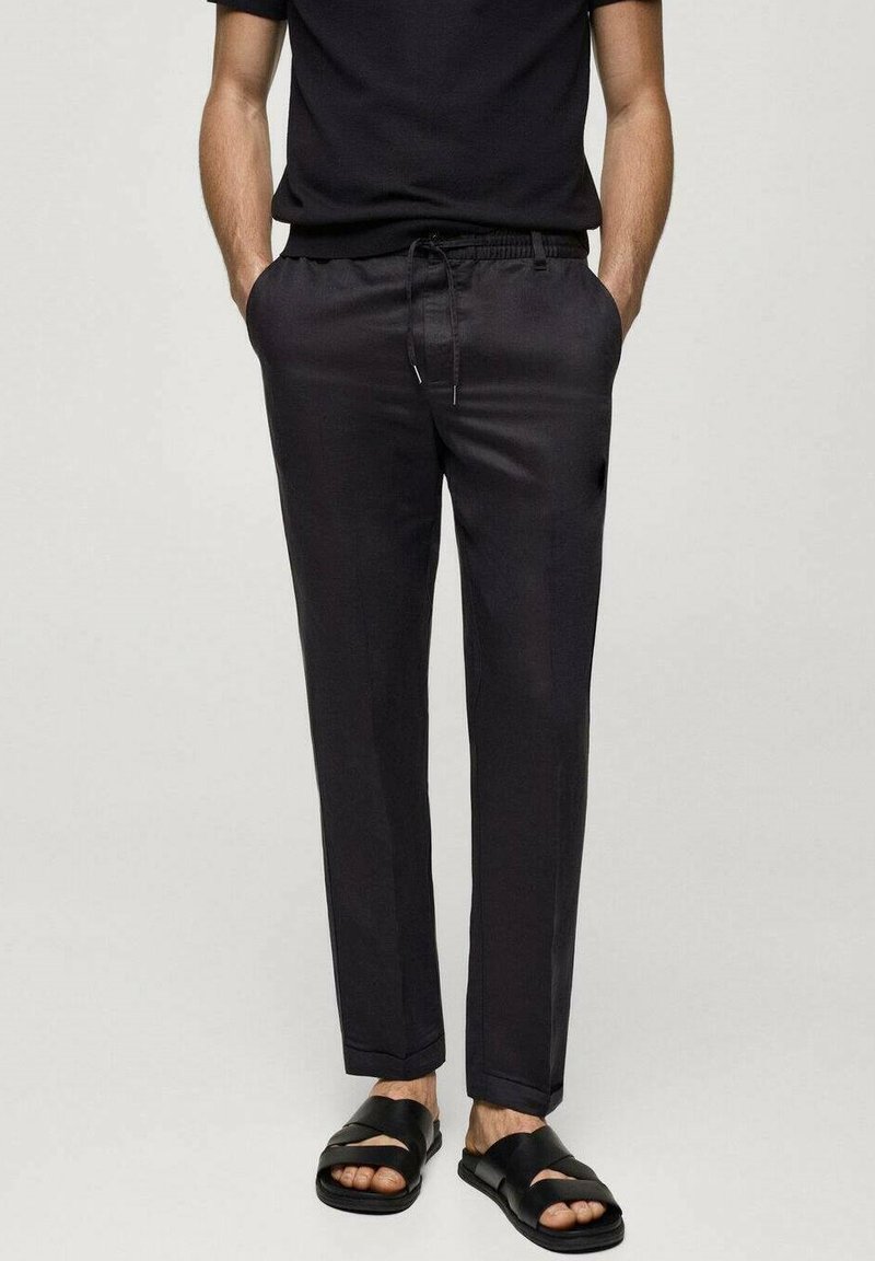Dark gray, lightweight trousers with a drawstring waistband, tapered fit, and subtle sheen, paired with black sandals.