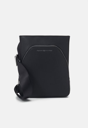 Zwarte leren crossbodytas met verstelbare schouderriem, zilveren gesp en Tommy Hilfiger-logo op het voorvak.