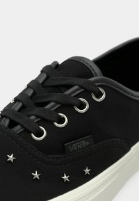 Τα αθλητικά παπούτσια Black Vans διαθέτουν ελαστική σόλα, υφασμάτινο πάνω μέρος, ασημένιες οπές, μαύρα κορδόνια και ασημένιες αστέρια ως διακοσμητικά στη πλευρά.