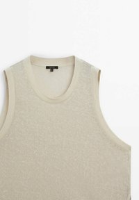 Gilet tricoté beige sans manches avec encolure ronde et bords côtelés, posé à plat sur un fond blanc.