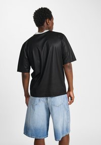 Black short-sleeve shirt with subtle vertical stripes and a white collar, paired with light blue denim shorts featuring an ombre effect.