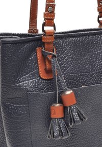 Marineblauwe leren tote bag met textuur en bruine accenten, voorzien van een franje-detail en een zak aan de voorkant. Verstelbare schouderbanden.