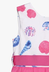 Vestido de algodón con fondo blanco adornado con patrones de conchas marinas en rosa y azul, y una cintura elástica suave en rosa.