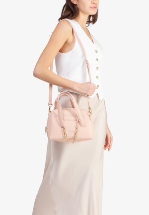 Piccola borsa a tracolla rosa realizzata in materiale testurizzato, con doppio manico, tracolla staccabile e dettaglio in catena dorata, esposta su uno sfondo bianco.