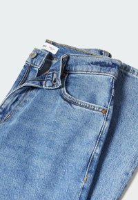 Jean en denim bleu clair plié avec poche avant visible, bouton et fermeture éclair sur fond blanc uni.