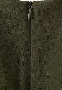 Tissu vert foncé avec une surface texturée, doté d'une fermeture éclair le long du dos central.