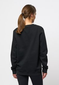 Zwarte sweatshirt met lange mouwen, ronde hals en geribde manchetten. Gemaakt van een katoenmix, met een soepele textuur en een relaxte pasvorm.