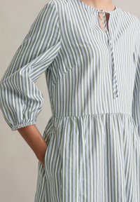 Gestreepte jurk met groene en lichtblauwe lijnen, met een ronde halslijn, knoopsluiting, elastische mouwen en een gathering taille met zakken.