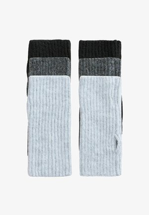 Keturi poros megztų kojinių, esančių juodos, tamsiai pilkos, šviesiai pilkos ir baltos spalvų, su riebiu raštu ir kontrastingais spalvų blokais.