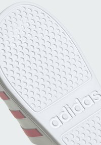 Podeszwa buta Adidas z teksturowanej białej gumy, z różowymi paskami po bokach oraz wytłoczonym logo.