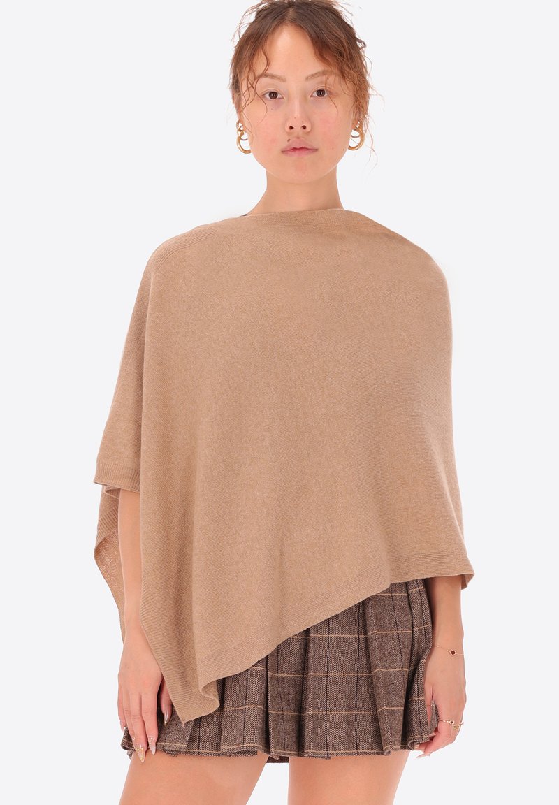 Poncho beige realizzato in morbido tessuto, caratterizzato da un design asimmetrico e svasato con maniche corte. È noto per la sua superficie liscia e lo stile minimalista.