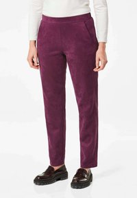 Paarse suède broeken met een slim fit, voorzien van zijzakken en subtiele stikdetails. Gecombineerd met donkere, stevige instappers.