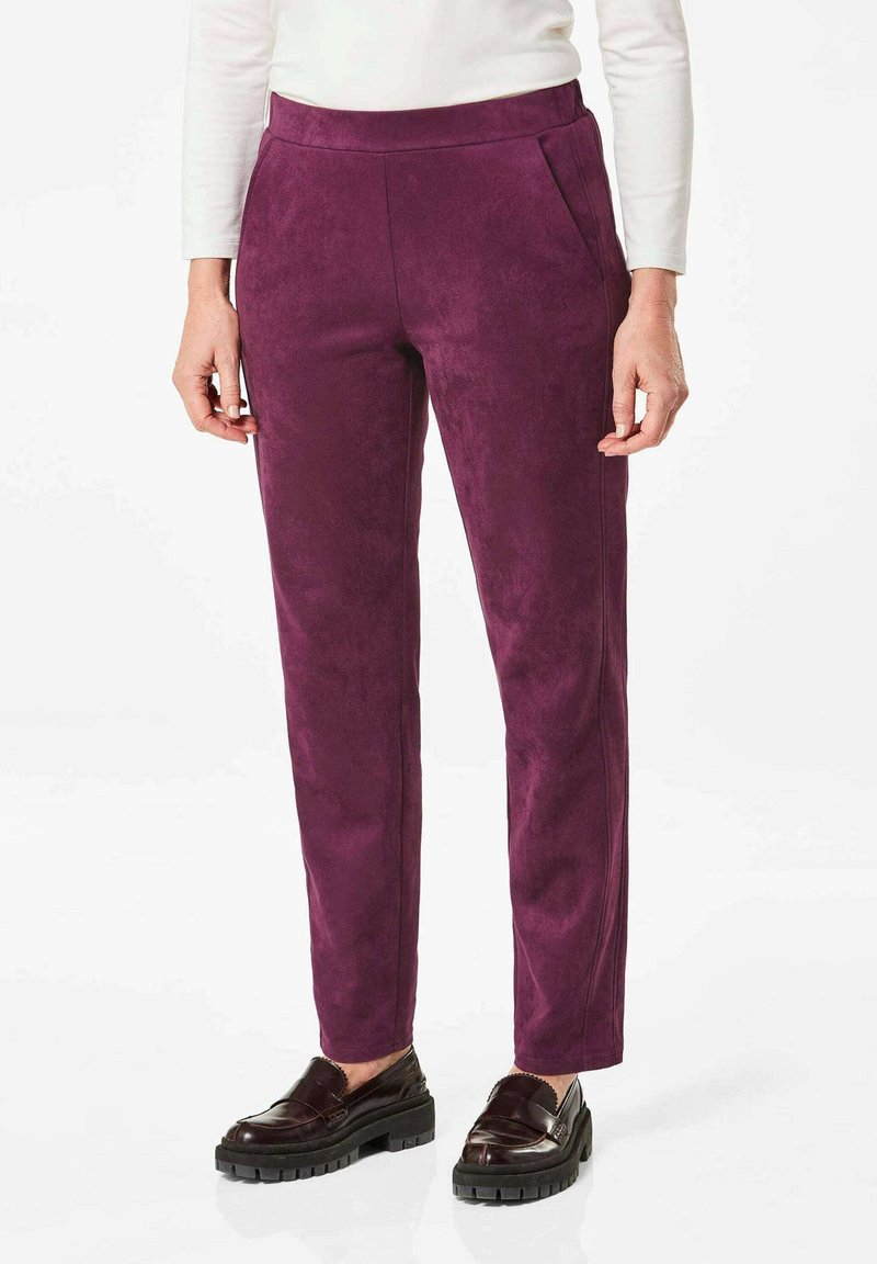 Paarse suède broeken met een slim fit, voorzien van zijzakken en subtiele stikdetails. Gecombineerd met donkere, stevige instappers.