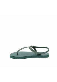 Chancla verde con suela texturizada, que presenta correas cruzadas y pequeños acentos de hardware. Fabricada con un material duradero y flexible.