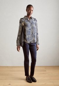 Navy patterned button-up shirt with long sleeves, paired with slim-fit navy pants and black loafers, complemented by a black shoulder bag.