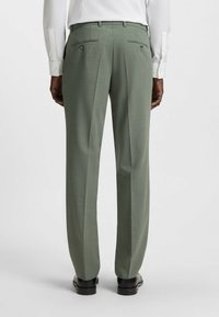Maßgeschneiderte Hosen aus leicht grünem Stoff. Merkmale sind ein flacher Bund, zwei hintere Taschen mit Knöpfen und eine glatte Textur. Geeignet für formelle Anlässe.