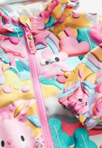 Veste de pluie colorée avec des motifs d'étoiles, de cœurs et de personnages de dessins animés. Matériau : tissu léger et durable avec une fermeture éclair rose.