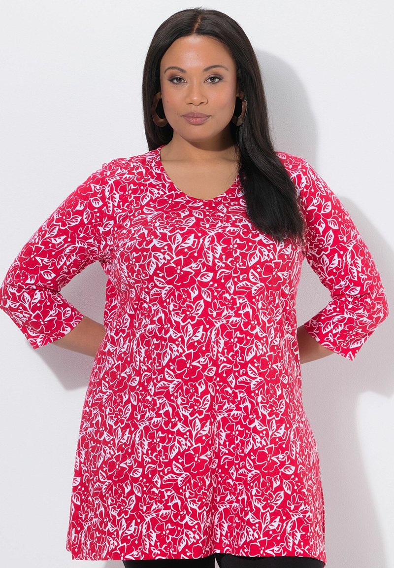 Red tunic featuring a floral print in white, three-quarter sleeves, round neckline, and a relaxed fit, made from a smooth fabric.