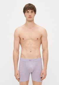 Boxer briefs lilases com uma textura suave, apresentando um design ajustado e uma cintura elástica larga em relevo com "GAP."