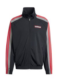 Veste de survêtement noire avec col montant, fermeture éclair à l'avant et poignets élastiques. Présente des bandes latérales rouges et grises et un logo "adidas" sur la poitrine.