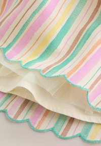 Tissu à rayures verticales pastel en rose, jaune, vert et marron, avec des bords festonnés ornés de surpiqûres turquoise et une couche de maille blanche.