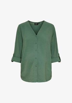 Roheline tekstureeritud pluus V-kaelusega, esipainutus ja üleskeeratud varrukatega. Valmistatud kergest kangast, omab lõdva lõikega.