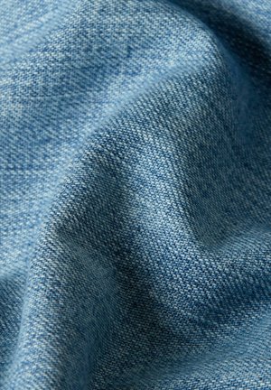 Close-up of light blue woven fabric with visible texture and soft folds creating gentle shadows.