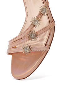 Sandalo in oro rosa con tre accenti gioiello, dotato di cinturini metallici lucidi e una finitura iridescente liscia sulla soletta.