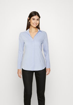 Light blue long-sleeve shirt with button-down collar, front buttons, and smooth fabric. Paired with black pants, no patterns or accents.