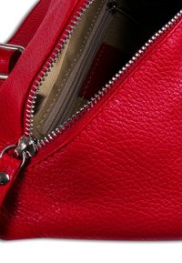 Rode leren tas met een gestructureerd oppervlak, voorzien van een zilveren rits en een binnenzak. De rits is deels geopend, waardoor een beige voering zichtbaar is.