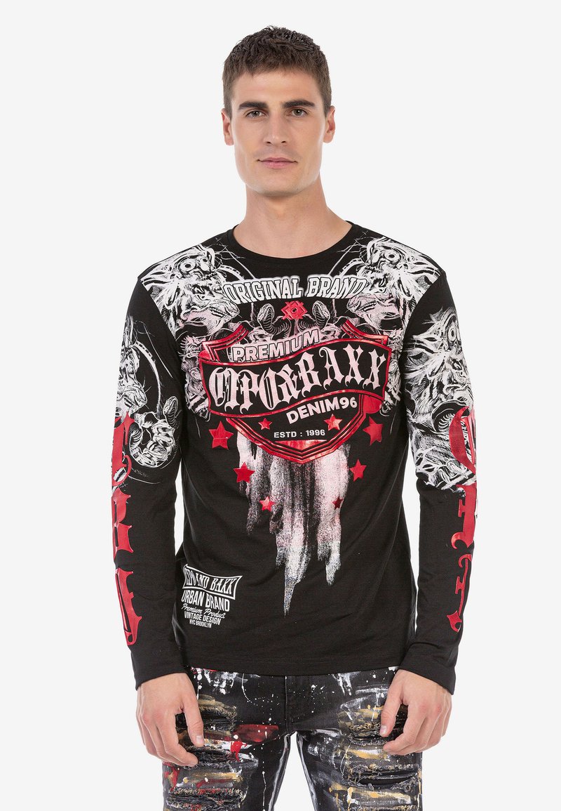 Schwarzes Langarm-T-Shirt mit roten und weißen Grafikdrucken, das über komplexe Designs, Logos und Details mit einem abgenutzten Textur verfügt.